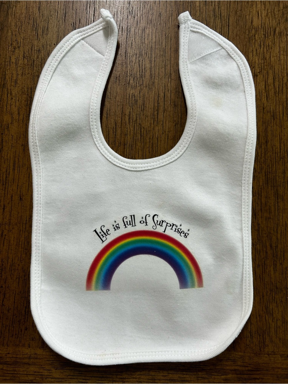 NEW White Baby Bib with Rainbow Graphic - "Life is full of Surprises"